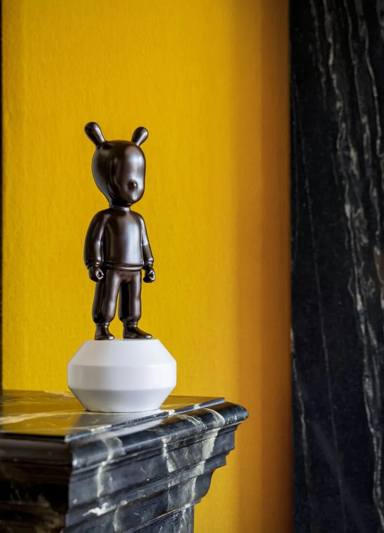 Brown Guest figurine on a white base against a yellow wall