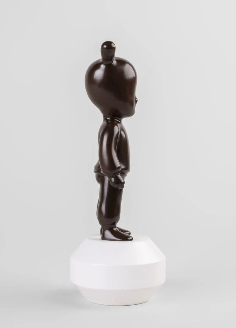 Brown Guest figurine on a white base against a white background