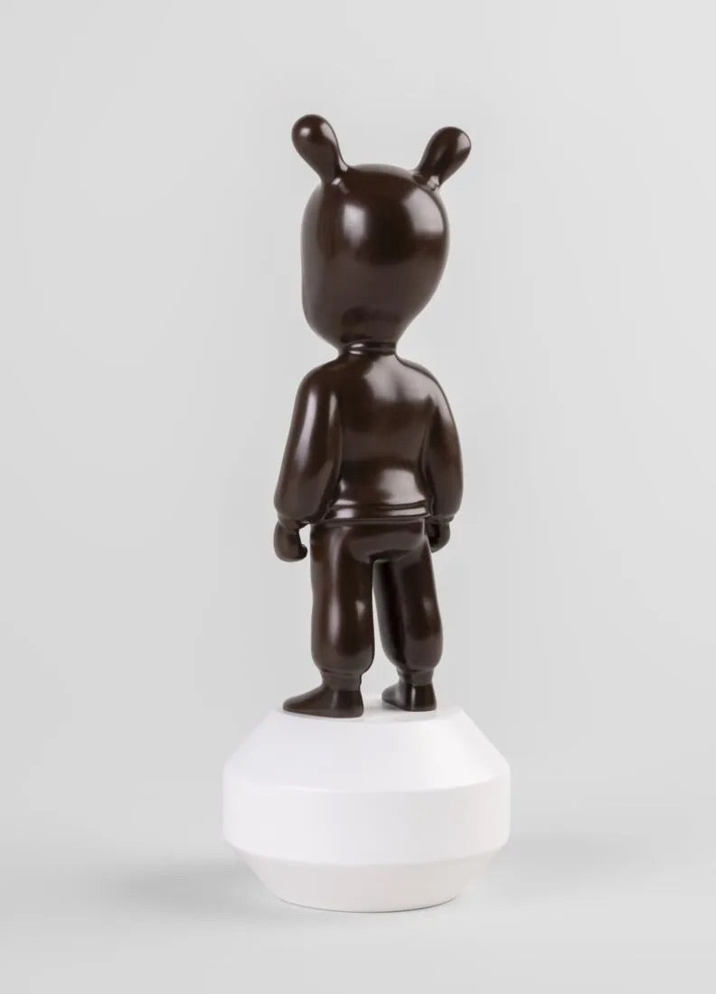 Brown Guest figurine on a white base against a white background