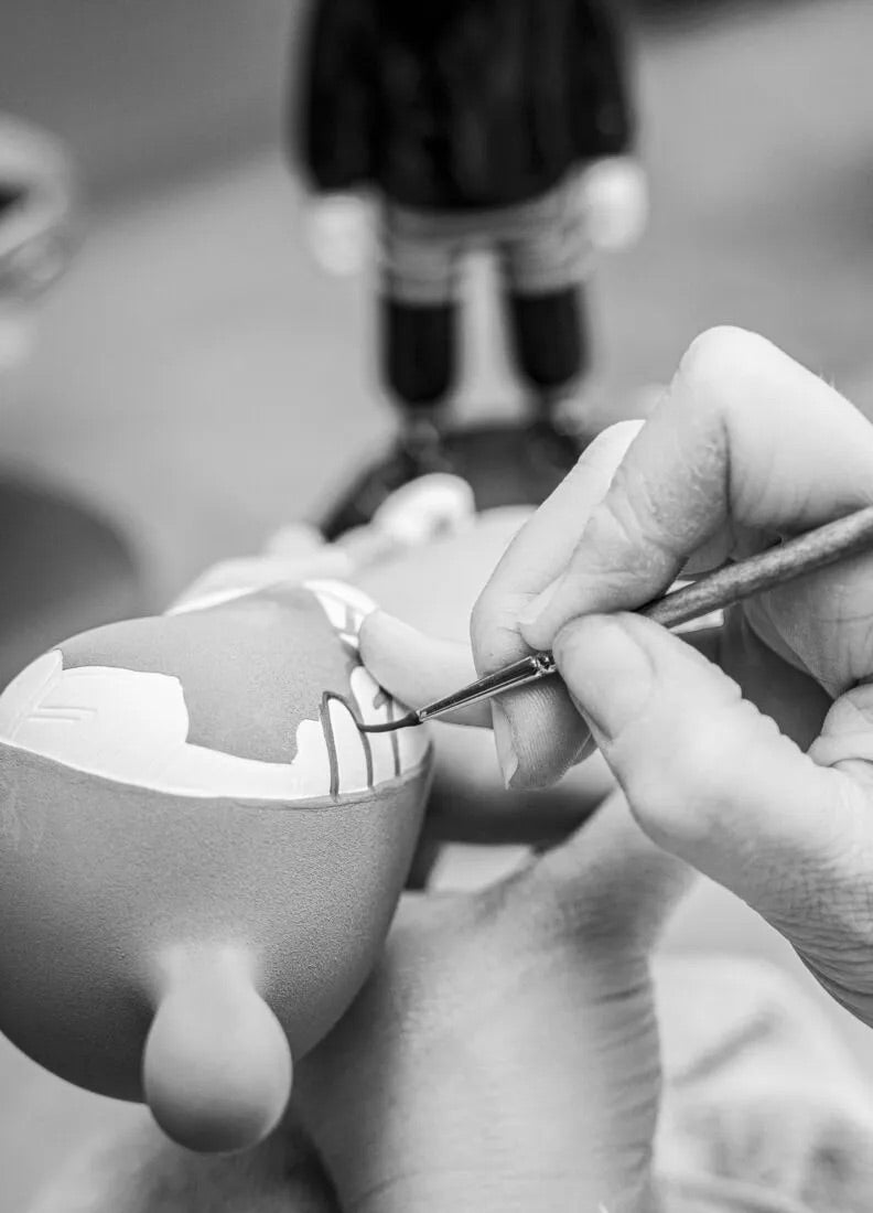 Person painting a small ceramic item with a brush, with a blurred background
