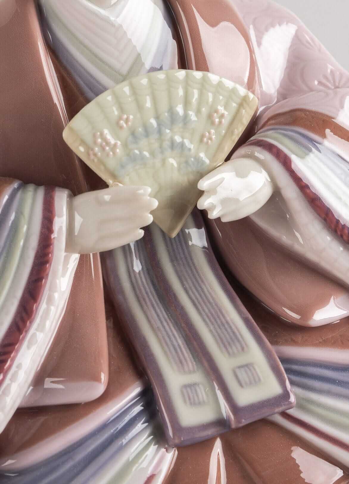 Close-up of a handmade porcelain Hina doll figurine with delicate fan, showcasing traditional Japanese craftsmanship.