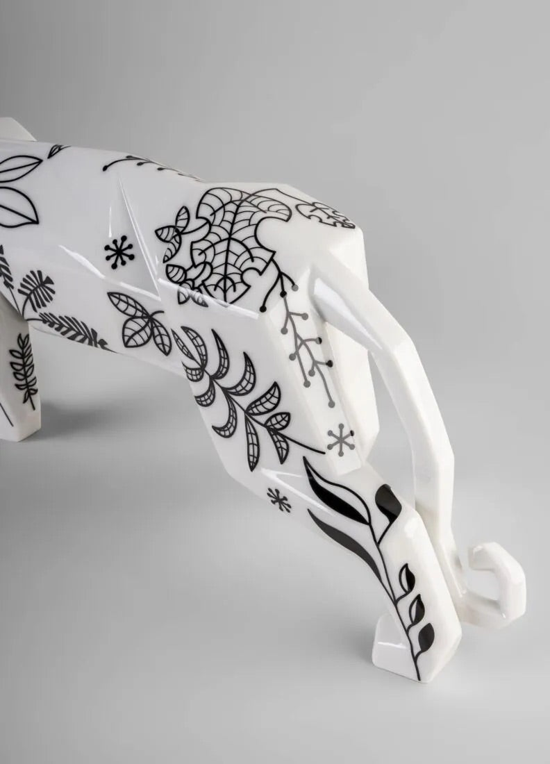 White porcelain panther figurine with black floral patterns on a gray background