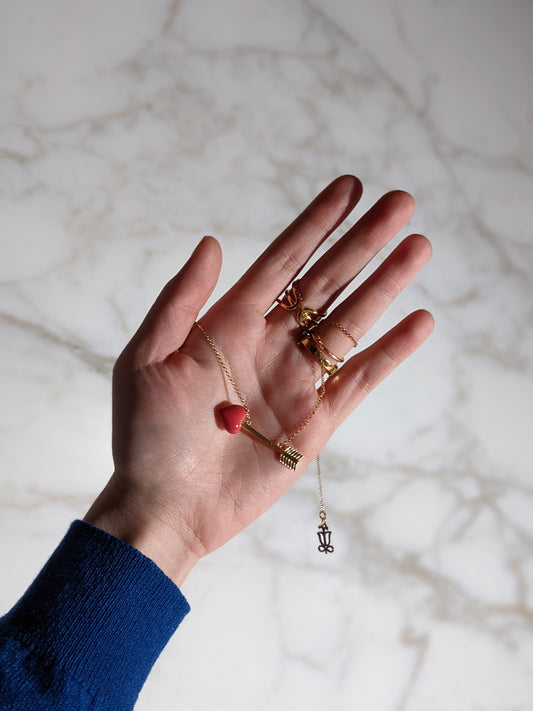 Crush Pendant Necklace by Formfluent, displaying a red porcelain heart on a gold-plated chain, held in a hand.