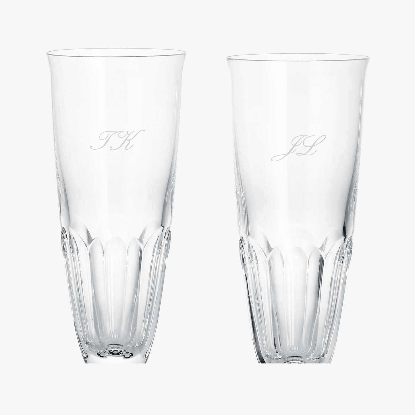Two clear Baccarat glasses with engraved initials on a white background