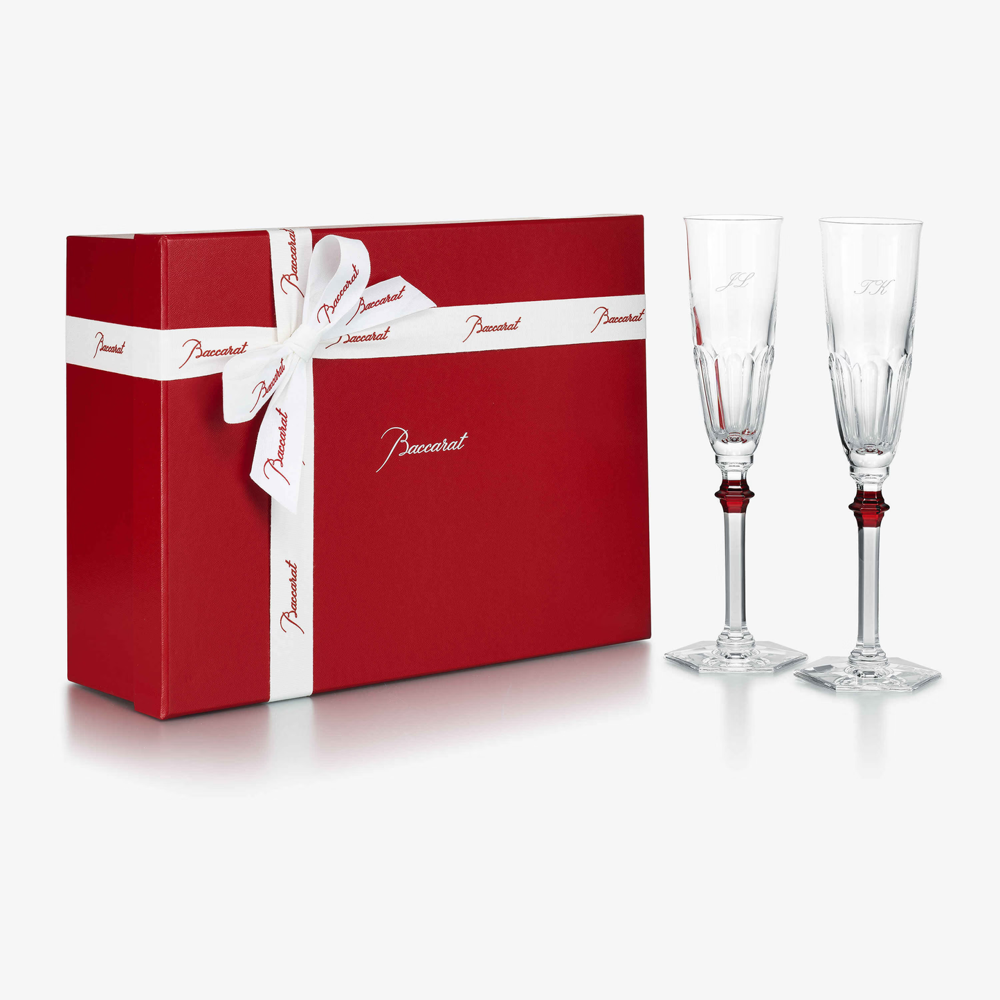 Red gift box with white ribbon and two champagne flutes on a white background