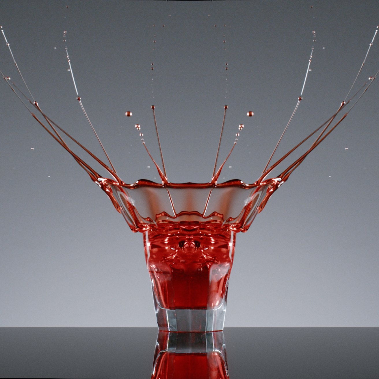 One clear Baccarat glass tumbler holding a red liquid cocktail inside amongst a grey background.