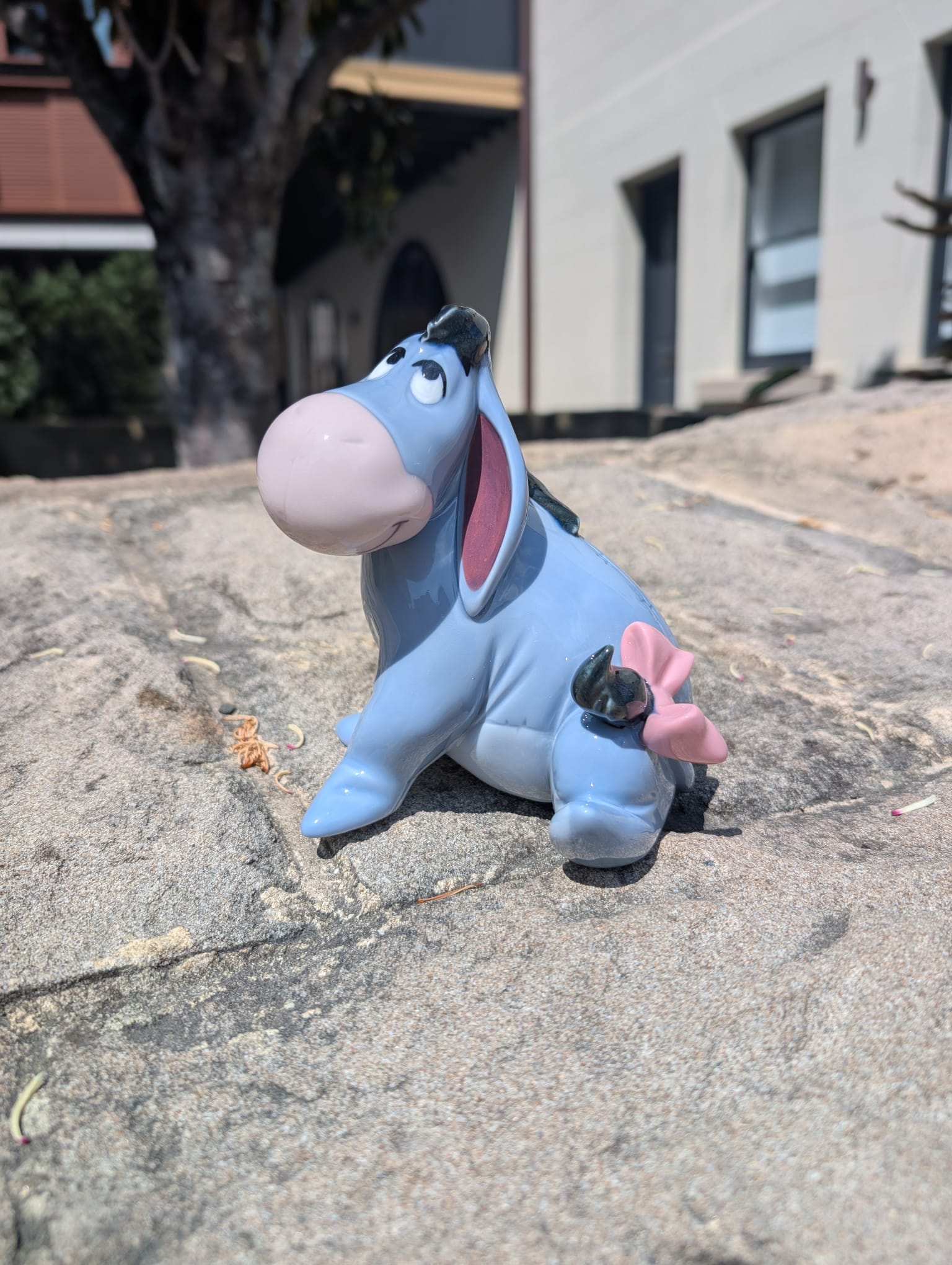 Eeyore figurine on a concrete surface with a building in the background