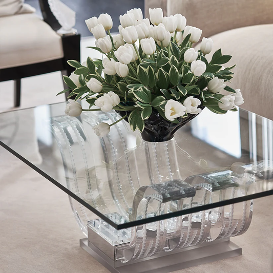 Modern living room featuring a Lalique glass coffee table, white tulips in black vase, beige sofa, and natural light—ideal for luxury interior design lovers.