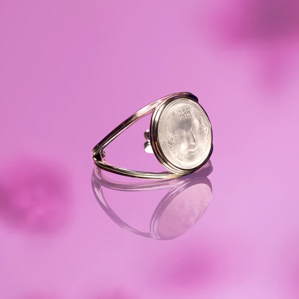 Elegant Lalique silver bracelet with an engraved round crystal centerpiece on a reflective purple surface