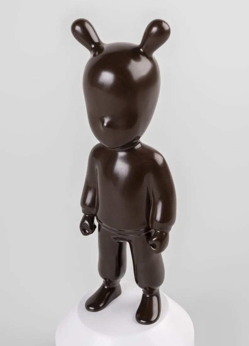 Brown Guest figurine on a white base against a white background