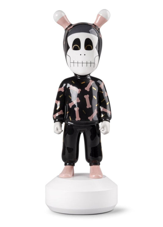 A stylized collectible figurine of a character wearing a black and pink patterned hoodie and black pants, standing on a white circular base against a white background.