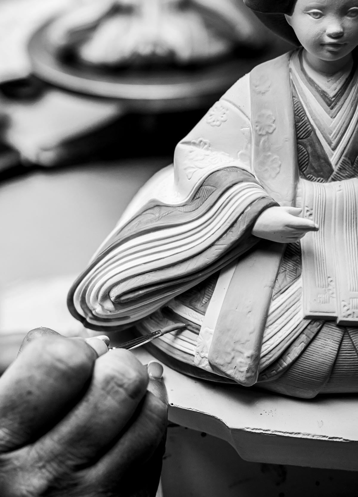 artisan handcrafting a delicate beige and pink Hina doll figurine, showcasing traditional Japanese craftsmanship in porcelain.