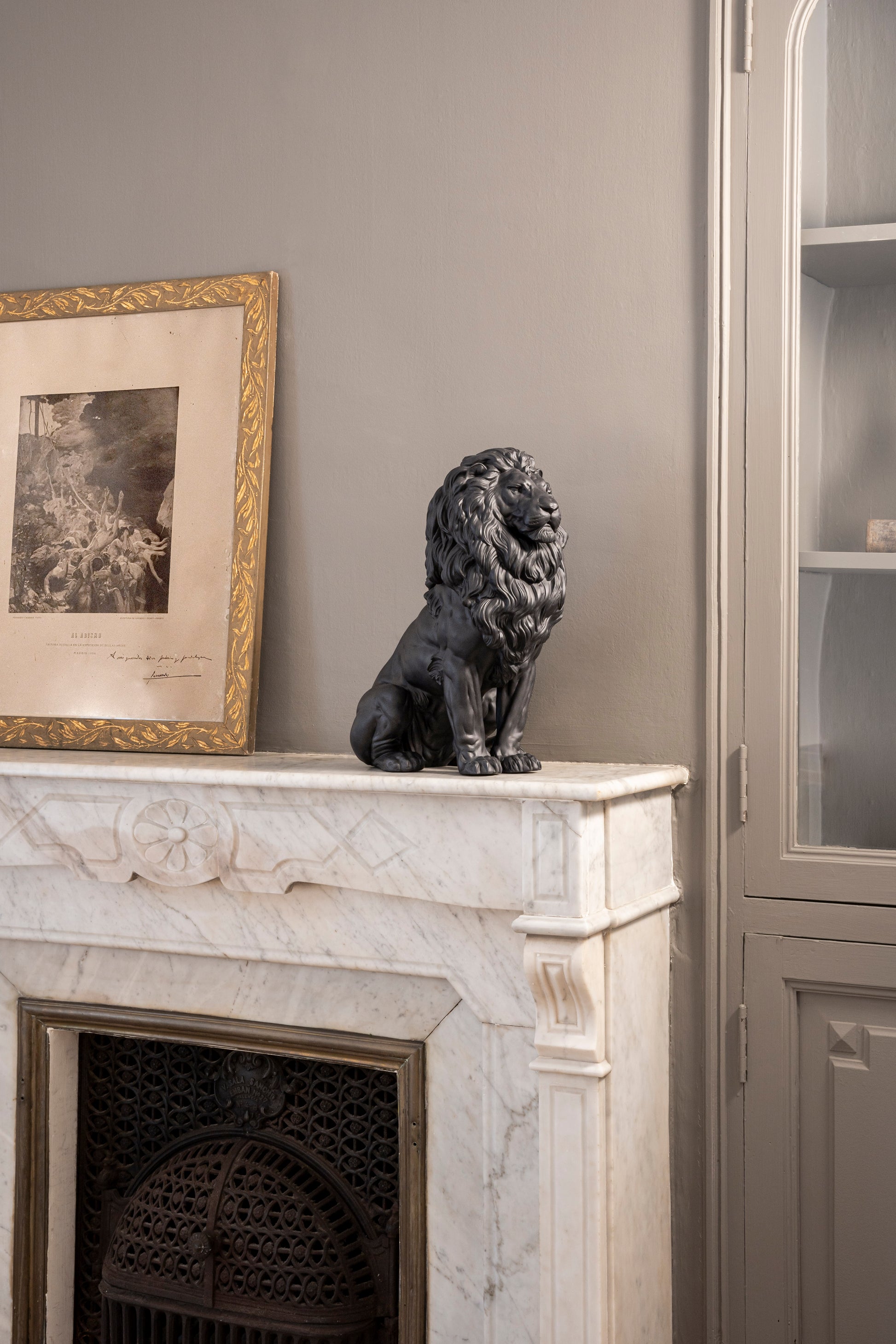 Lladró Majestic Lion Sculpture in matt black porcelain displayed on a marble fireplace, exuding strength and elegance.