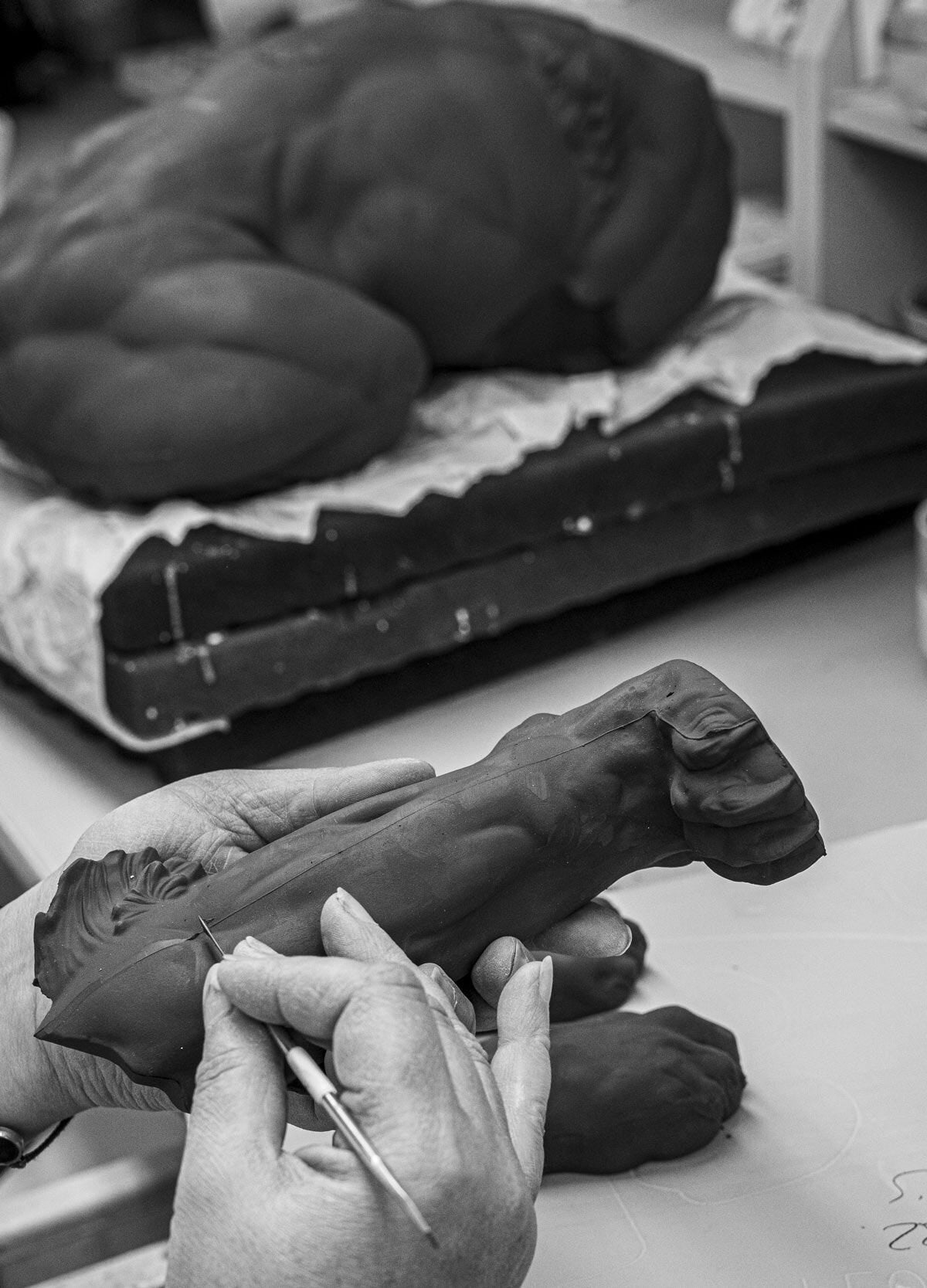 Artist shaping a detailed sculpture from clay, showcasing craftsmanship and artistry in the creation process.