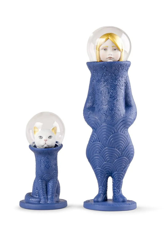 Blue porcelain figures with glass spheres containing a cat and a woman on a white background
