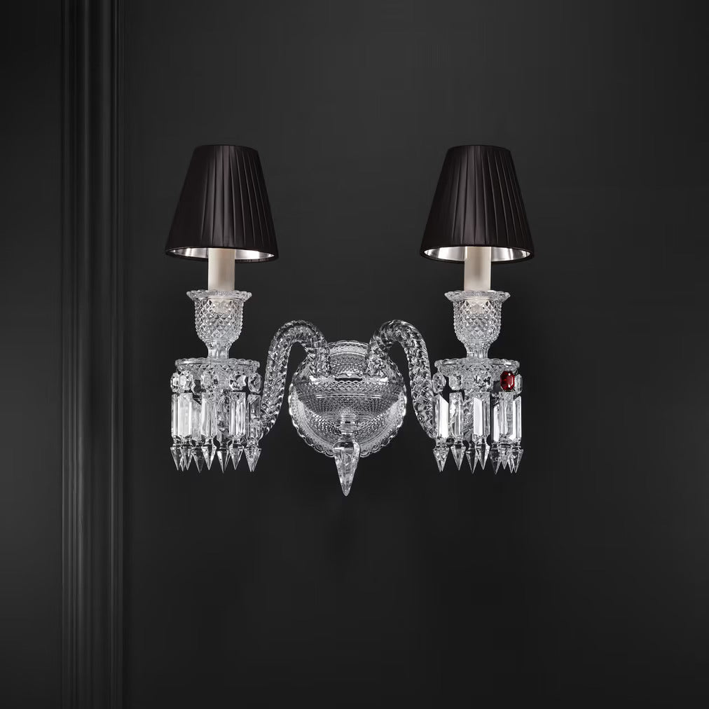 Decorative wall sconce with crystal design and black lampshades on a dark background