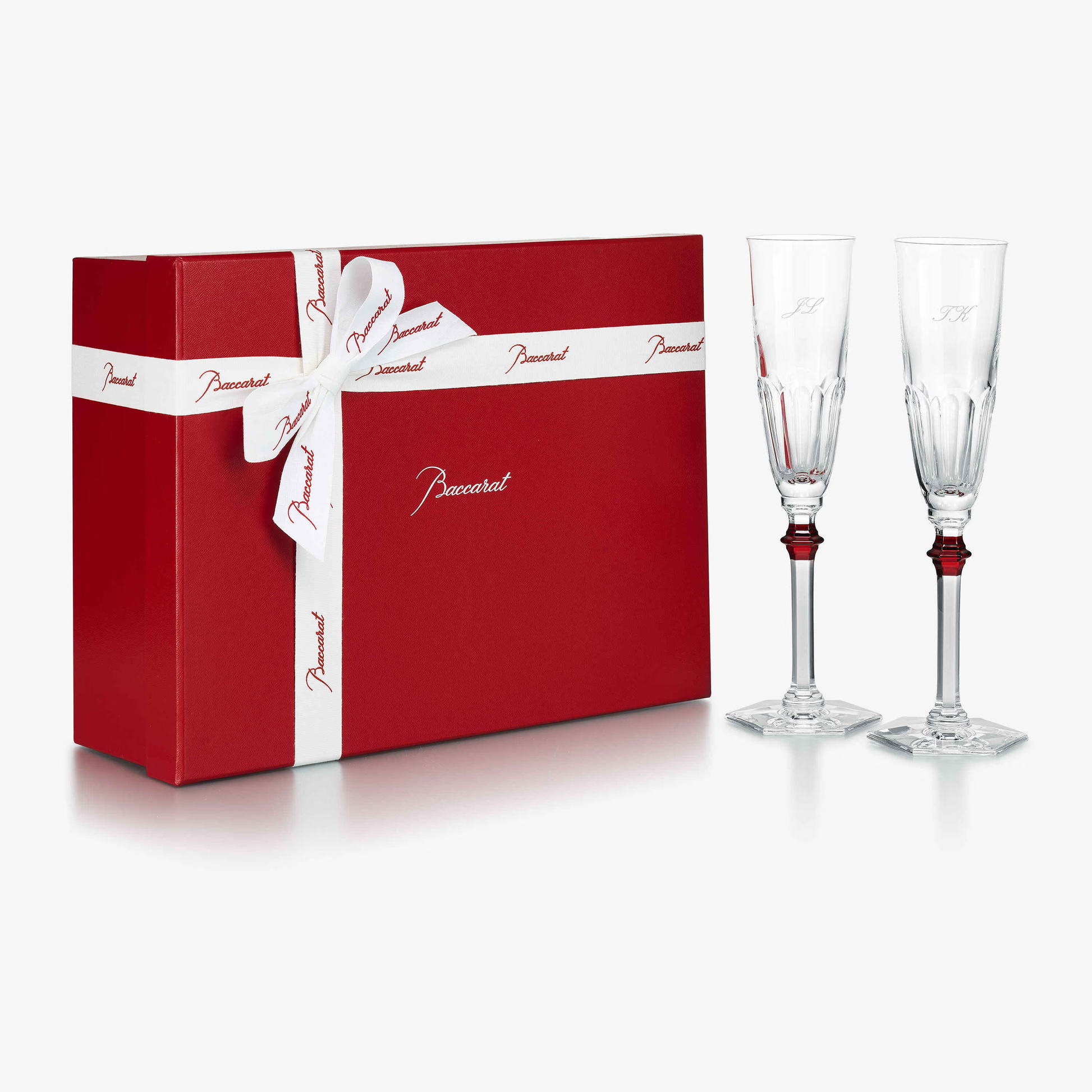 Red gift box with white ribbon and two champagne flutes on a white background