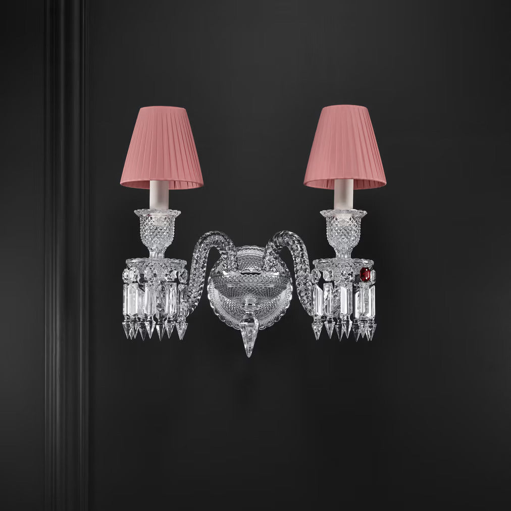 Decorative wall sconce with crystal details and pink lampshades on a black background