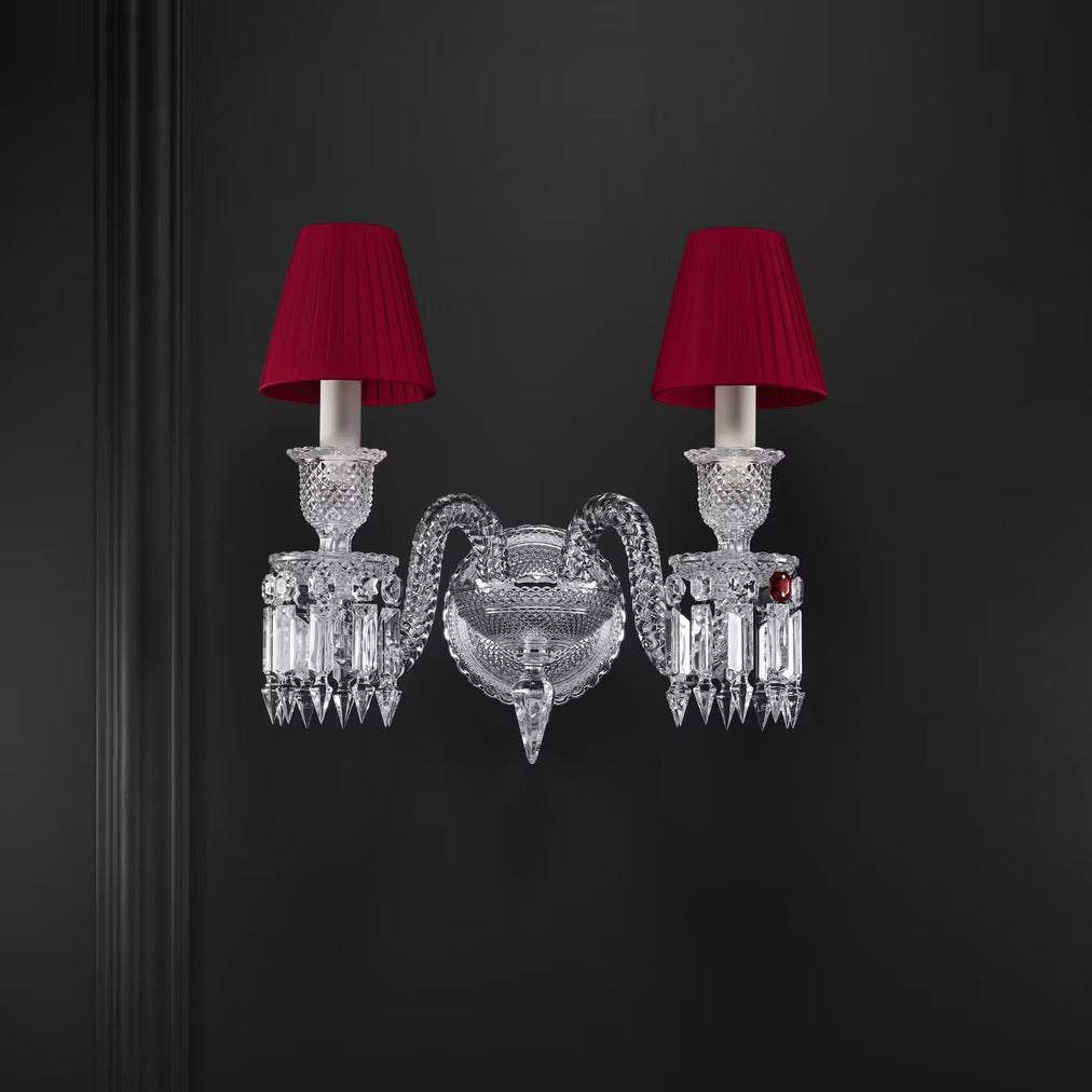 Decorative wall sconce with crystal design and red lampshades on a dark background
